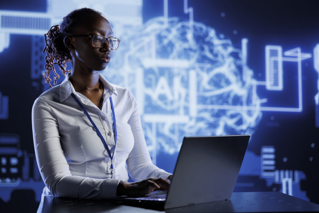 A focused professional working on a laptop in front of a digital neural network display labelled "AI," symbolising artificial intelligence research and innovation.