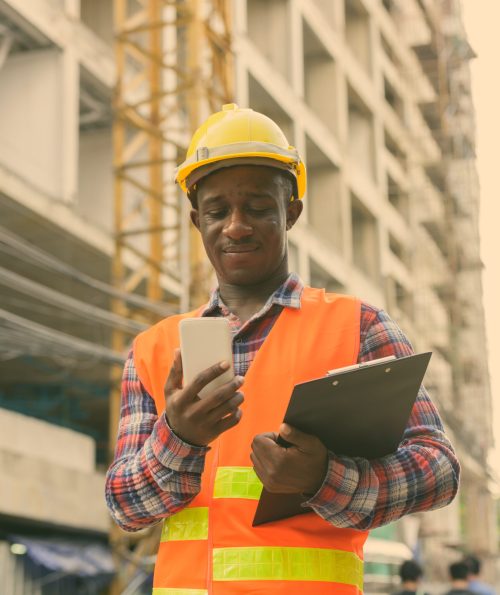 A construction worker in a safety vest and hard hat using a smartphone to access HR support and payslips on-site.